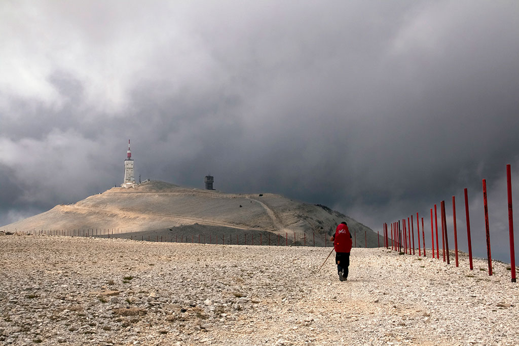 Un randonneur marche sur un sentier de cailloux vers le sommet du mont Ventoux