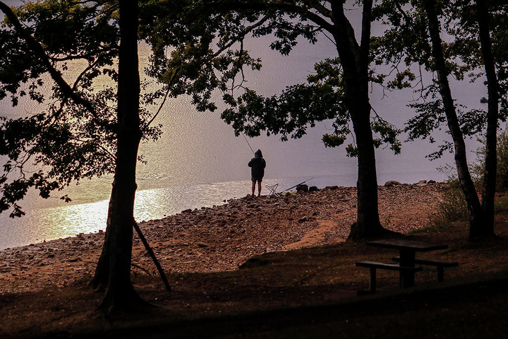 Pêcheur au bord du lac de Marcillac-la-Croisille en Corrèze au coucher du soleil