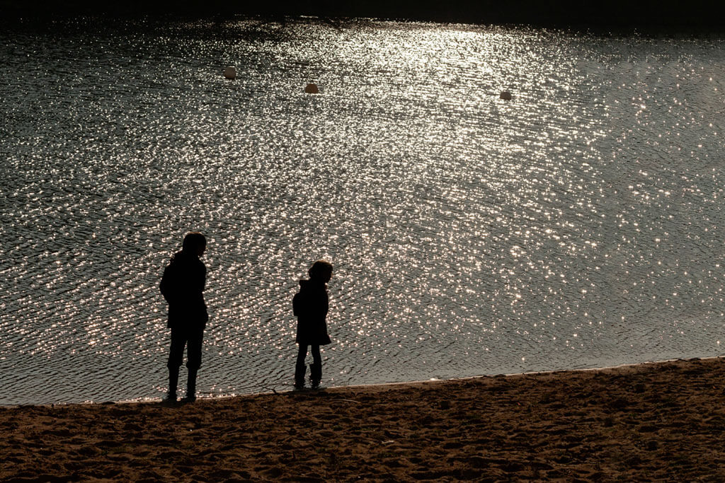 Deux enfants en ombre chinoise au bord d'un étang lumineux