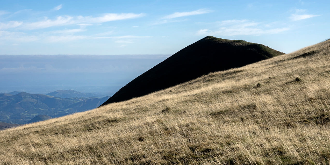 Herbe blonde devant le sommet noir et pointu d'une montagne dans les Pyrénées