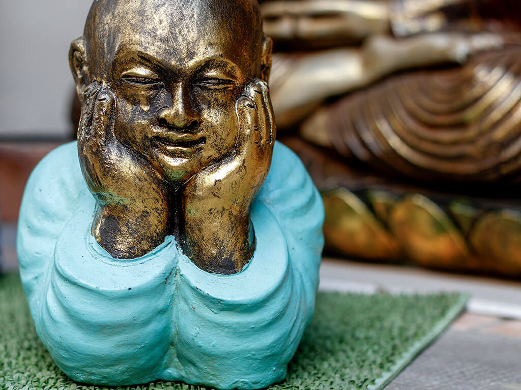 Un bouddha bleu et or repose sa tête dans ses mains