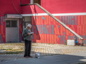 homme-lit-journal-facade-batiment-rouge-tirana