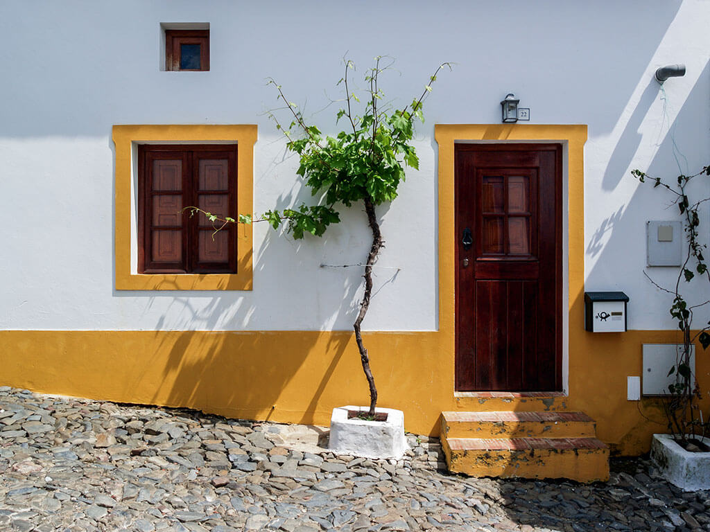 facade-maison-blanche-jaune-arbuste-rue