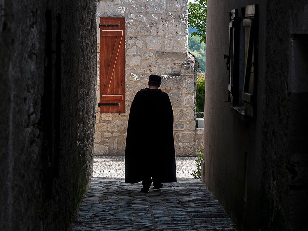 homme-cape-ruelle-village-pierre