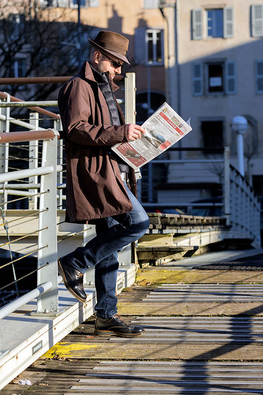 homme-debout-chapeau-lit-journal-passerelle
