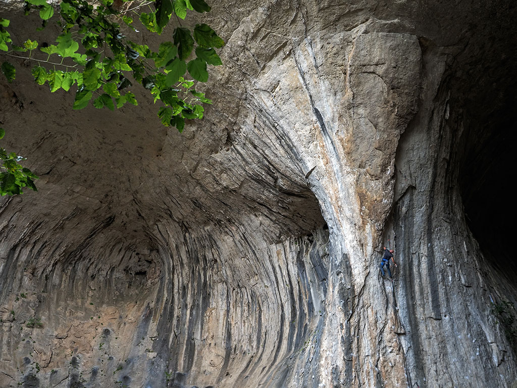 Un homme escalade la paroi d'une grotte