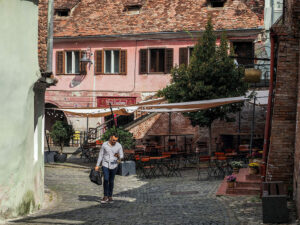 homme-marche-rue-pavee-maison-rose-sibiu-roumanie