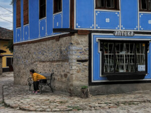 femme-assise-banc-maison-bleue-koprivchtitsa-bulgarie