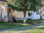 Un homme assis sur un banc dans une rue du village de Viscri en Roumanie