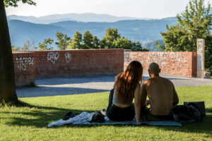 couple-assis-pelouse-parc-tour-horloge-graz-autriche