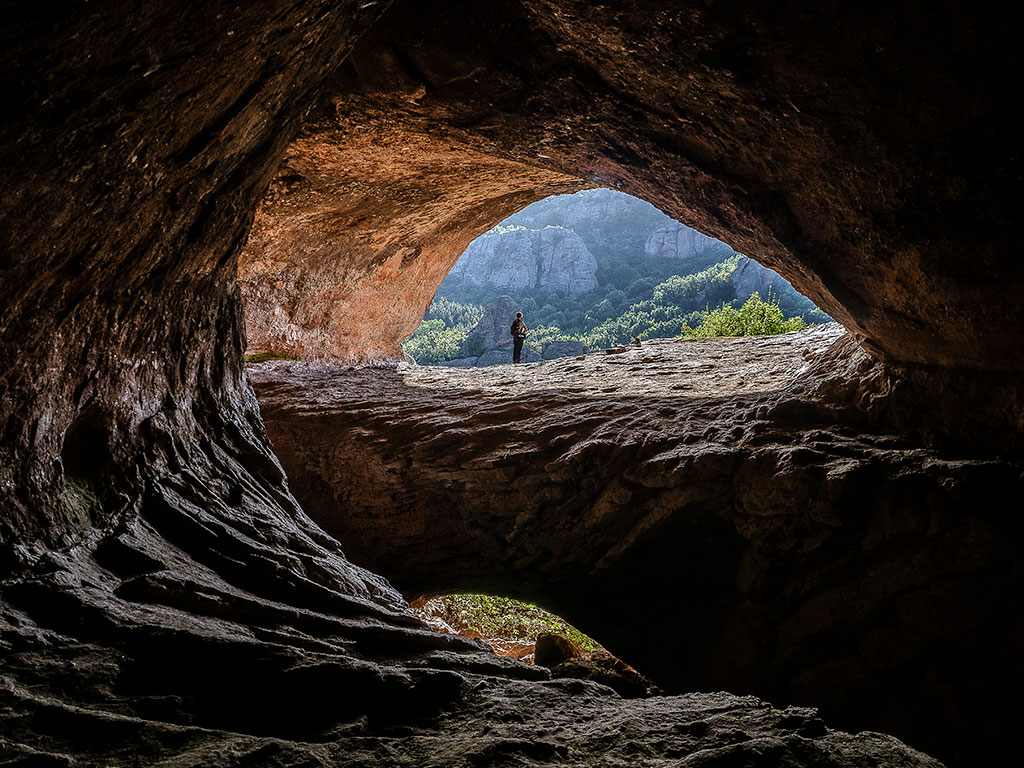 Femme se tenant debout à l'entrée de la grotte de Lepenista à Belogradtchik en Bulgarie
