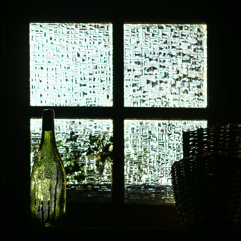 Silhouette de bouteilles devant une fenêtre à carreaux