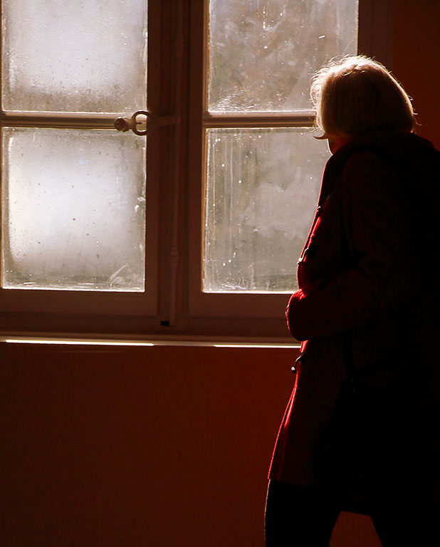 Contre-jour d'une personne âgée devant une fenêtre