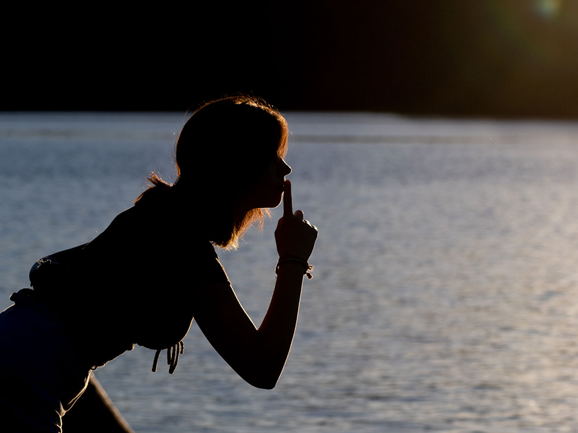 Silhouette d'une jeune fille penchée en avant au bord de l'eau