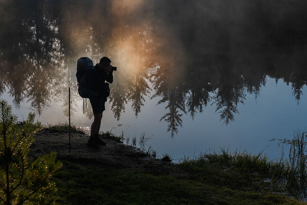 Silhouette d'un photographe-randonneur au bord d'un lac