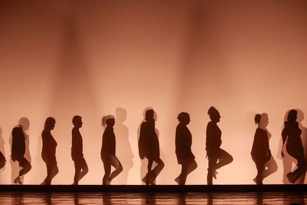 Silhouettes d'une troupe de danseurs sur scène.